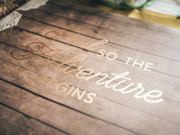 A wood table with the message "and so the adventure begins"