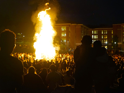 People standing around a bonfire at night on Erickson Field at UMBC