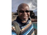 headshot of Assaf Anyamba, sunglasses on, striped shirt.